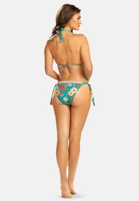 Bikini w kwiatowym wzorze w kolorze turkusowym z zawiązywaniem na szyi, z koronkowymi majtkami i bocznymi zapięciami na troczki. Pokazana tylnia strona.