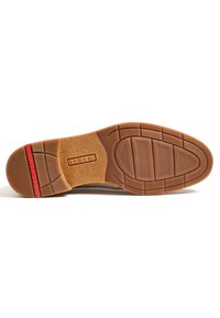 Semelle de chaussure en caoutchouc marron avec un motif antidérapant texturé et un accent rouge. Présente un logo de marque clair et une forme contournée pour le confort.