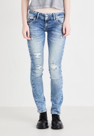 Light blue distressed jeans with a slim fit, featuring multiple rips and a classic five-pocket design. Paired with black lace-up boots.