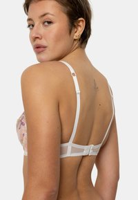 Soutien-gorge en dentelle dans des couleurs pastel avec broderies florales. Bretelles blanches ajustables, fermeture au dos par agrafes, et détails en résille transparente.