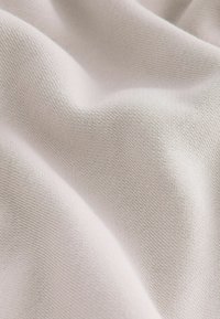 Tela beige clara con una textura suave, que presenta un patrón de tejido fino y una caída suave.