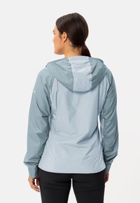 Lichte, waterdichte jas in twee tinten grijs. Heeft een capuchon, lange mouwen en elastische manchetten, met een gestructureerde afwerking.