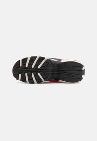 Black running shoe sole with rubber traction pattern; features a midsole in red and white, contrasting against the textured black upper.