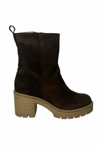 Botines de ante marrón con una suela gruesa y acanalada y un tacón apilado. Presentan un cierre de cremallera y un pequeño tirador en la parte trasera.