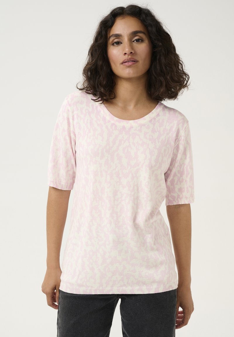 Pull rose à manches courtes avec un motif animal subtil, encolure ronde et texture douce, associé à un jean noir.