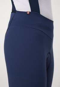 Navy cycling shorts with a smooth, stretchy fabric. Features a fitted design and a distinctive red logo accent near the waistband.