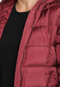 Chaqueta acolchada color granate con capucha, diseño acolchado y cierre de cremallera. Material ligero con textura suave y acabado brillante.