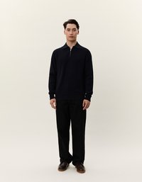 Navyfarbener gestrickter Pullover mit einem Viertelreißverschluss, langen Ärmeln und strukturiertem Finish, kombiniert mit schwarzen Hosen und braunen Schuhen.