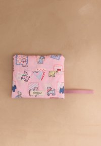 Sulankstytas rožinės spalvos audinio maišelis su šunų raštu, Cath Kidston prekės ženklu ir rožine kilpa rankena ant smėlio spalvos fono.