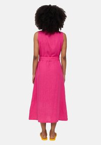 Rosa Leinen-Hemdkleid ohne Ärmel mit einem Gürtel in der Taille, das knielang ist und eine fließende Silhouette hat. Einfacher, texturierter Stoff.