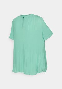 Blouse vert menthe côtelée avec un col rond, des manches courtes et un détail de bouton au niveau du col. Tissu doux et fluide avec une coupe décontractée.