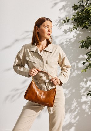 Bruine leren handtas met een gebogen vorm en een kort handvat, voorzien van een gladde textuur en subtiele stiksel details.