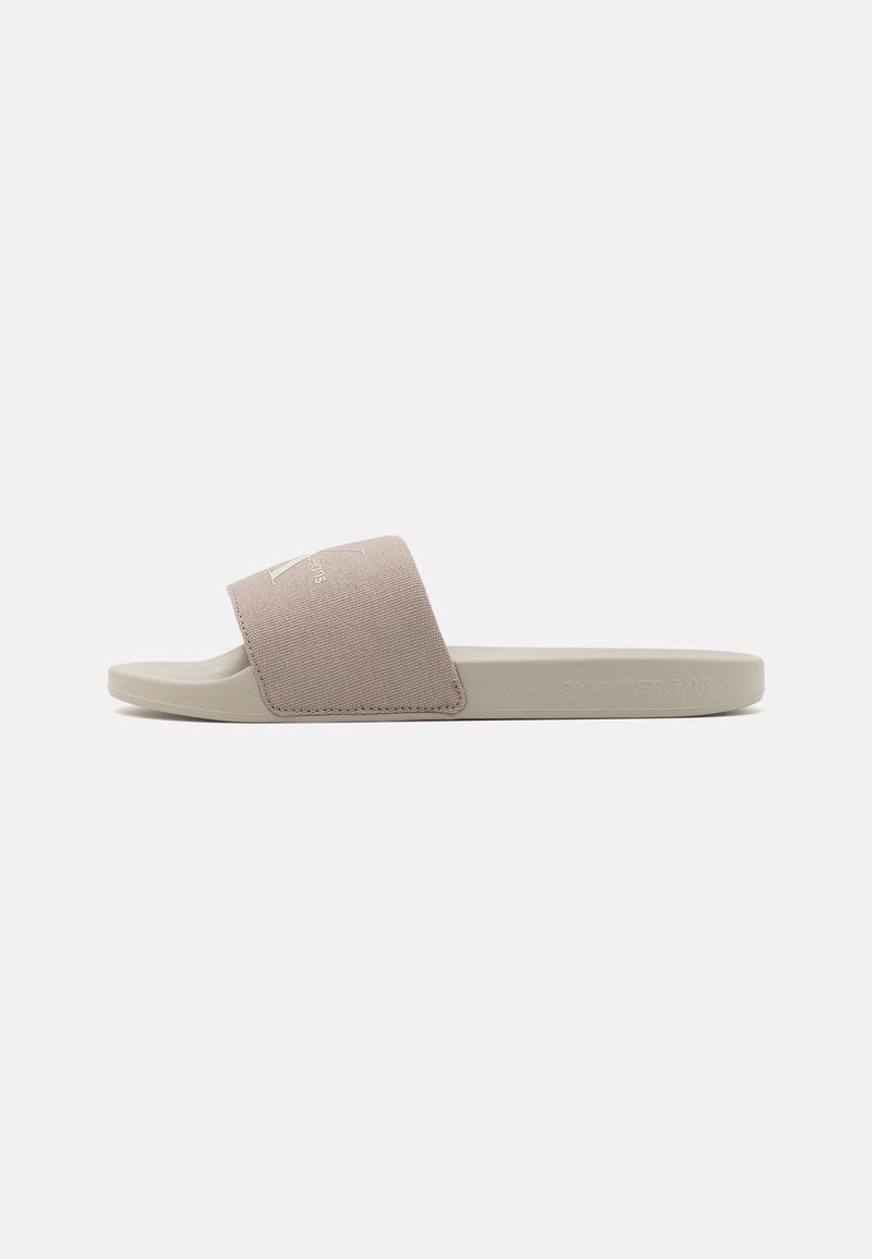 Svijetlosivi klizni sandal s mekanim, svijetlopinkastim gornjim dijelom od tkanine i ravnim, teksturiranim đonom. Sadrži detalj s logotipom na trakama.