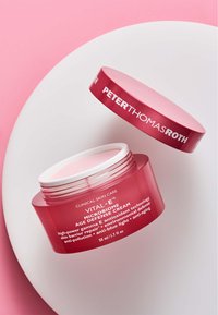Rosa plastburk med vit lock, som har "Peter Thomas Roth"-logotyp och produktinformation i vit text. Innehållet är en ljus rosa kräm.
