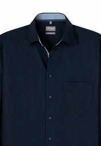 Marineblaue Hemdbluse mit einer bequemen Passform, ausgestattet mit einer gemusterten Krageninnenseite und einer Brusttasche. Glatte Stofftextur mit dunklen Knöpfen.