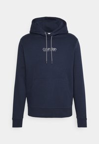 Felpa blu navy in misto cotone con tasca frontale, cappuccio con cordino e logo "Calvin Klein" bianco. I polsini e l'orlo sono rifiniti per garantire durata.