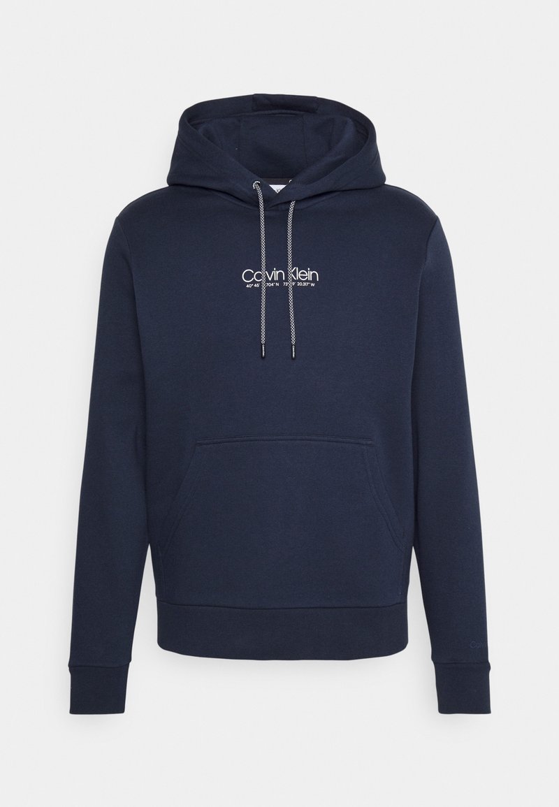 Felpa blu navy in misto cotone con tasca frontale, cappuccio con cordino e logo "Calvin Klein" bianco. I polsini e l'orlo sono rifiniti per garantire durata.