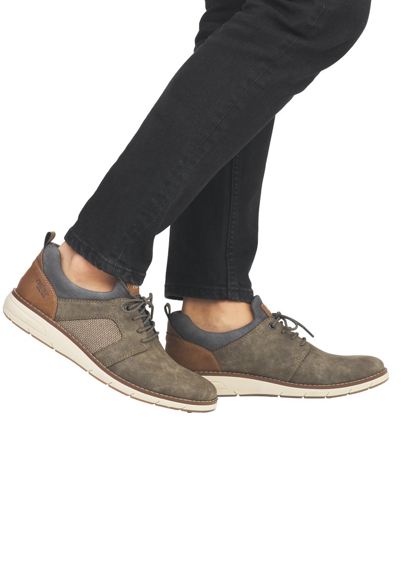 Chaussures pour hommes en daim vert olive, avec des accents gris et un talon en cuir marron. Elles sont dotées d'une semelle rembourrée et d'un design à lacets. Panneau latéral texturé.