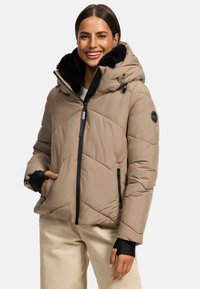Beige pufferjack met een zwarte nep-bont capuchon, diagonale doorgestikte patroon, ritszakken aan de voorkant en zwarte accenten op de manchetten en ritsen.