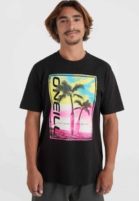 Camiseta de algodón negra con un gráfico colorido de palmeras sobre un fondo degradado en azul, rosa y amarillo. Diseño de logo rectangular.