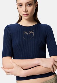 Top a coste navy con maniche corte; presenta un sottile design grafico sul petto. Il materiale sembra morbido con una silhouette aderente.