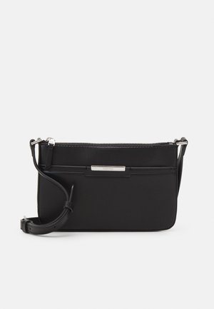 Sac bandoulière rectangulaire noir avec sangle réglable, fermeture éclair argentée et petite plaque logo Calvin Klein argentée sur le devant.