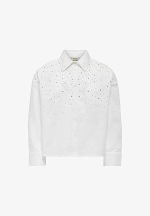 Witte katoenen shirt met een kraag, voorzien van zilveren studs langs de schouders en de bovenkant vooraan. Lange mouwen met knoopsluiting bij de manchetten.