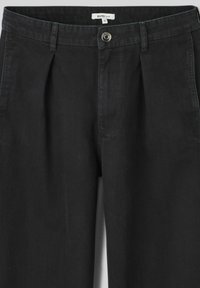 Pantalon en denim noir à coupe ample, avec fermeture à bouton, plis et une conception de ceinture simple. Pas de poches visibles.