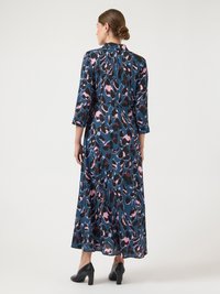 Ilga, laisvai krentanti suknelė mėlynu, rožiniu ir juodu gyvūnų raštu. Su trim ketvirčio ilgio rankovėmis ir apykakle. Dėvima su juodais aukštakulniais batais.