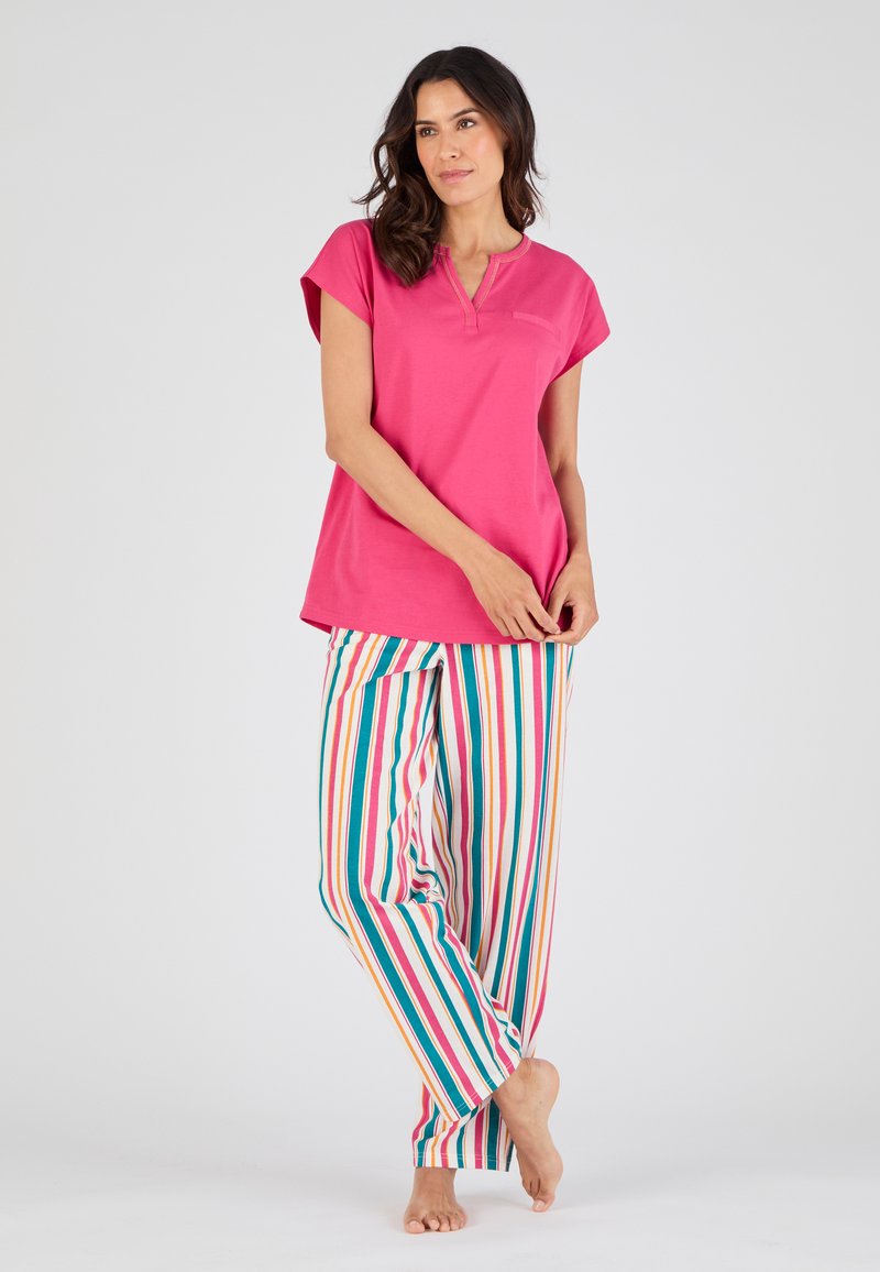 Haut rose à manches courtes avec un col henley, associé à un pantalon rayé multicolore avec des lignes verticales rouges, bleues et jaunes.