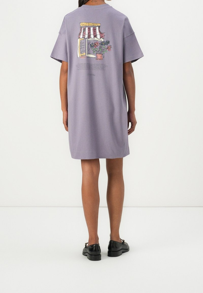 Světle fialové oversize tričkové šaty s krátkým rukávem. Ilustrace obchodu se stromy vzadu. Měkká bavlněná textura.