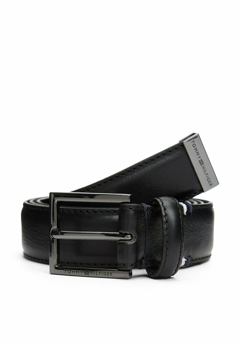 Zwarte leren riem met een glanzende zilveren gesp, met een gladde textuur en gestikte randen; voorzien van de merknaam "TOMMY HILFIGER" op het beslag.