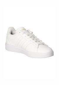 Hvid lav Adidas sneaker med snørelukning, tre sidelommer og guld Adidas logo på tungen, set i en vinkel.