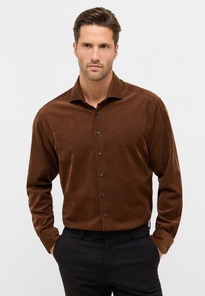 Bruine corduroy button-up shirt met een spread collar en zwarte knopen, lange mouwen en een gladde textuur, gedragen met zwarte broeken.