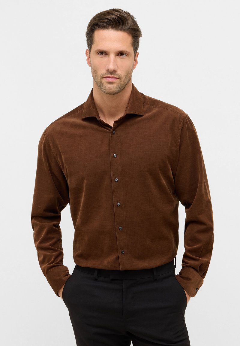 Bruine corduroy button-up shirt met een spread collar en zwarte knopen, lange mouwen en een gladde textuur, gedragen met zwarte broeken.