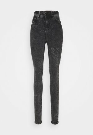 Jeans skinny de tiro alto en negro con efecto acid-wash, con cierre de botones y bolsillos frontales, exhibidos sobre un fondo blanco liso.