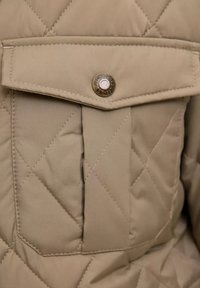 Bolsillo de tela acolchada beige con solapa y botón de presión de metal con la marca "JACK & JONES EST. 1990."