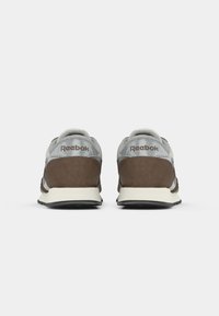 Hnedé semišové a šedé textilné tenisky s bielou medzipodrážkou, kontrastnou čiernou gumovou podrážkou a vyšitým logom "Reebok" na päte.