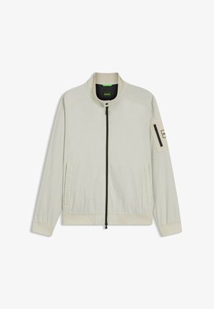 Giacca beige chiaro con zip, collo alla coreana, due tasche frontali, polsini elasticizzati e una tasca con zip sulla manica sinistra con l'etichetta "BOSS".