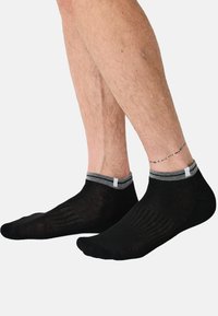 Calzini corti neri con polsino grigio a coste, caratterizzati da una texture liscia e un motivo a righe sottili lungo il piede.