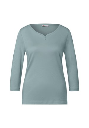 Camicia azzurro chiaro a maniche lunghe con scollatura rotonda, placket con due bottoni e una superficie morbida e liscia. Presenta un design a vestibilità rilassata.