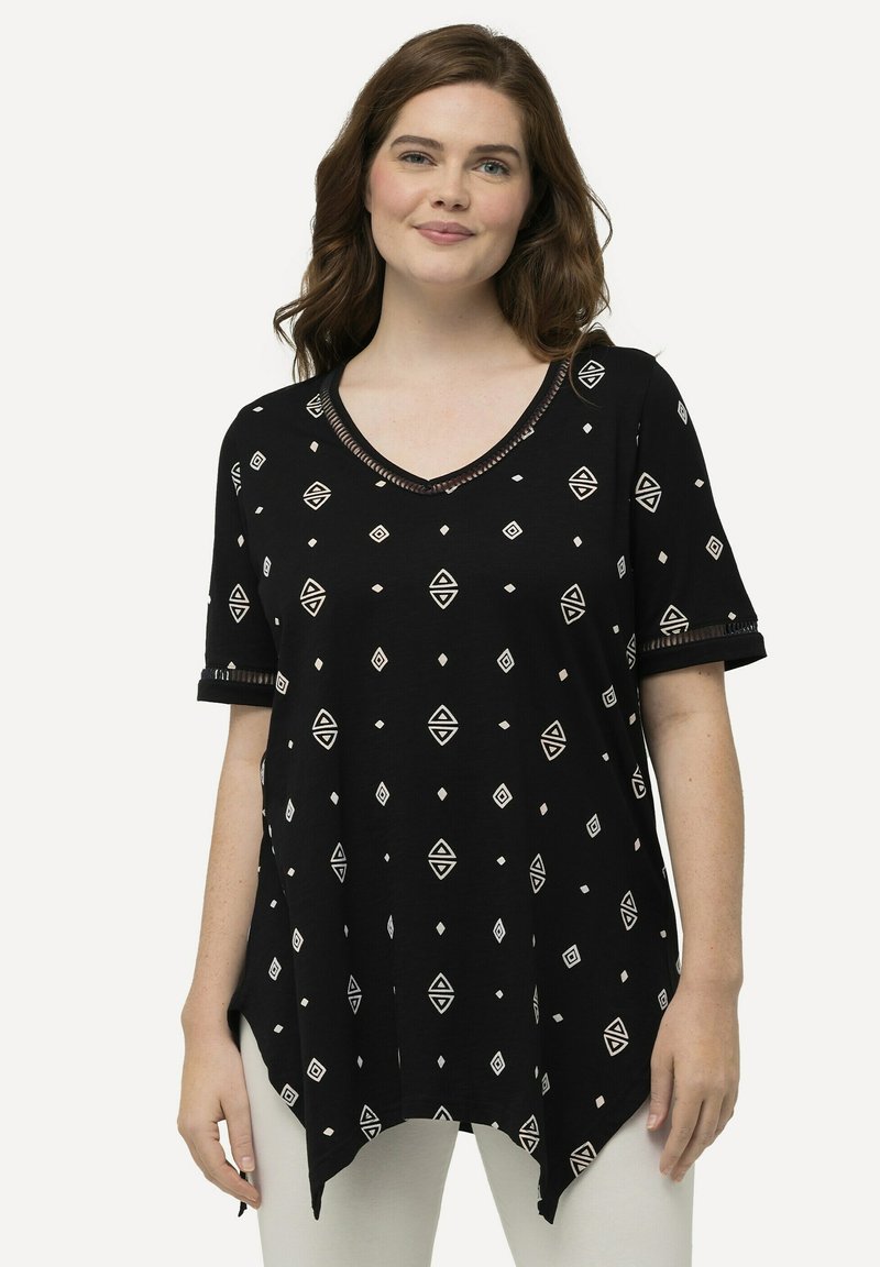 Túnica negra con escote en V que presenta patrones geométricos blancos, mangas cortas enrolladas y un dobladillo curvado para un ajuste relajado. Textura de tela suave.