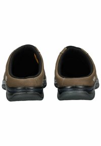 Hnědé semišové slip-on boty s černým polstrovaným límcem, gumovou podrážkou a švy. Otevřená špička s hladkým vnitřkem.