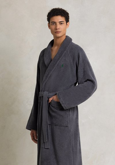 Γκρι μπουρνούζι φτιαγμένο από τσόχα με λαιμόκοψη τύπου σαλονιού, μακριά μανίκια, ζωνάκι για δέσιμο και μπροστινή τσέπη. Διαθέτει ένα μικρό πράσινο λογότυπο στο στήθος.