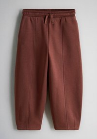 Rudos spalvos trumpintos sportinės kelnės su elastinga juosmens juosta ir raišteliu, priekyje ties vertikaliomis siūlėmis, ant vienspalvio fono.