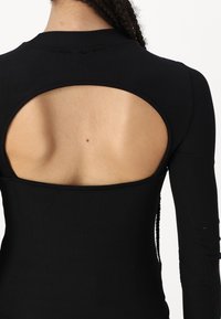 Black ribbed long-sleeve top featuring a large cut-out at the back, highlighting the skin in a smooth texture.