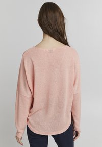Hellrosa, locker sitzender Strickpullover mit weitem Ausschnitt und langen Ärmeln. Verfügt über einen abgerundeten Saum und einen weichen, strukturierten Stoff.