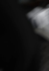 Black fabric with a subtle texture, partially obscures a white surface in the background. Focus is unclear, details are not distinguishable.