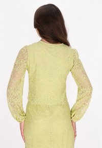 Rochie din dantelă de culoare verde pal, cu mâneci lungi din material transparent, modele florale și un corset ajustat cu un design scurt la spate.