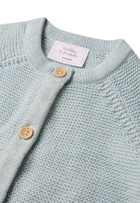 Cardigan lavorato a maglia azzurro chiaro con scollo rotondo, bottoni in legno e un'etichetta con i dettagli del marchio e della taglia. Tessuto morbido e strutturato.